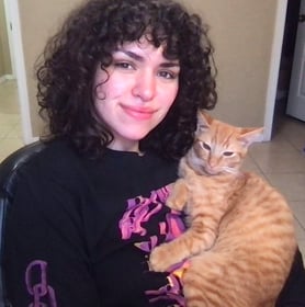 Team member poses with an orange cat she adopted from PVAS.